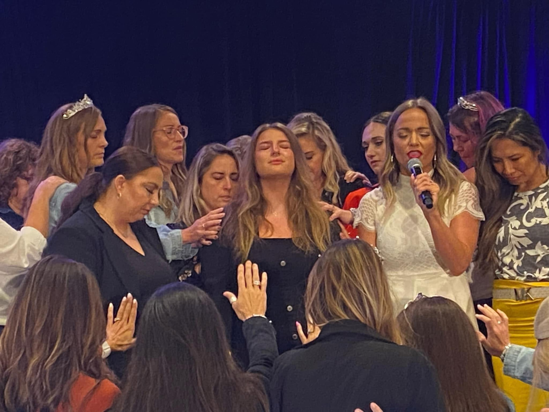 Molly Gomez praying with women at a faith based gathering